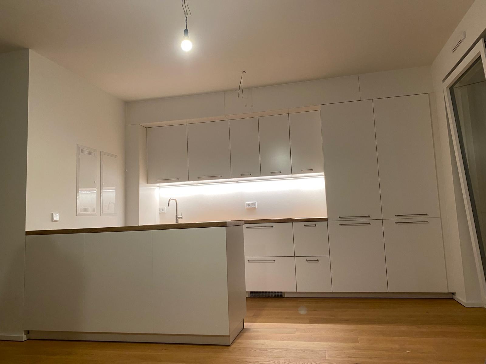 Weiße Einbauküche mit Holzarbeitsplatte und LED-Beleuchtung – Helfmann Küchenmontage